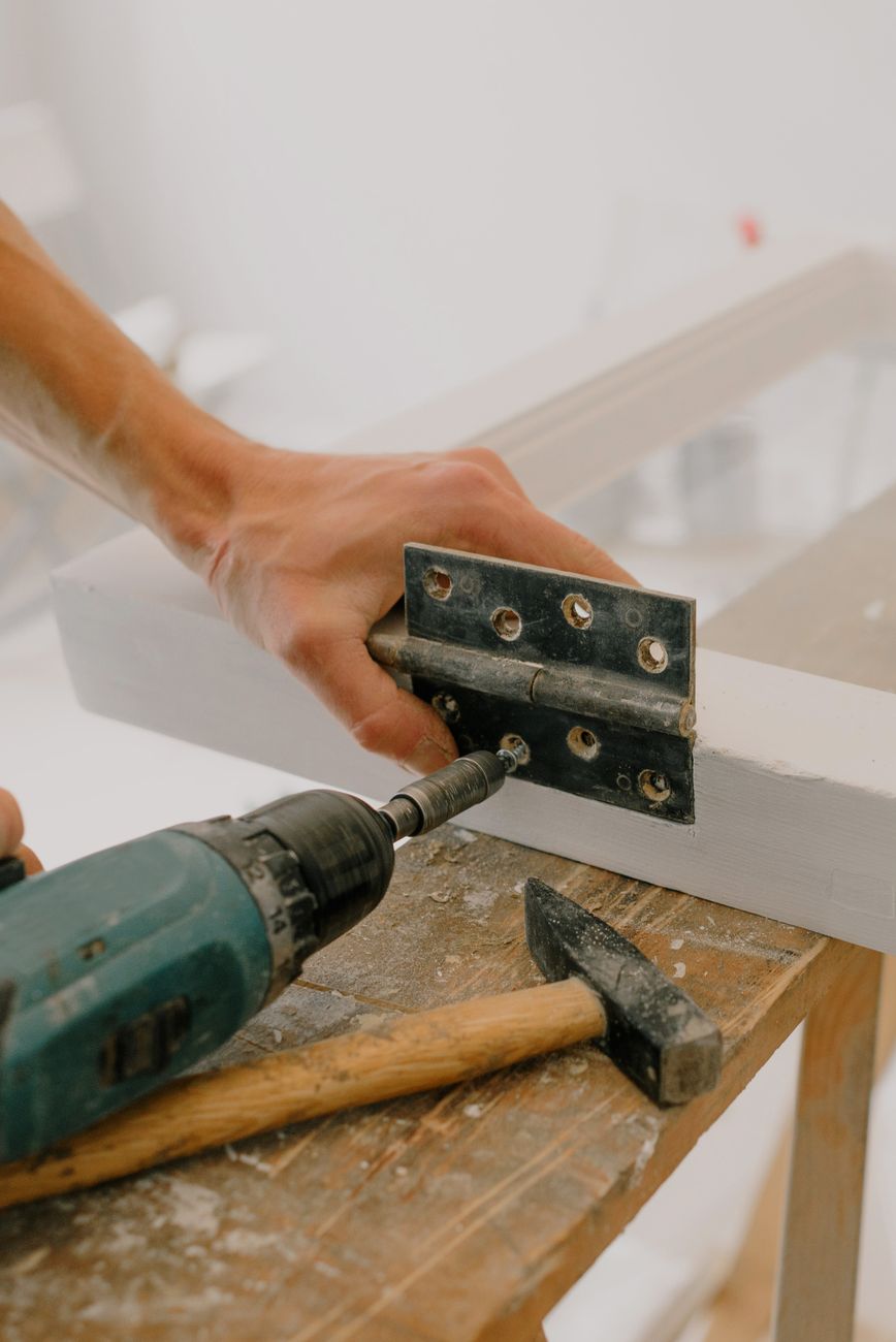 crop handyman fastening metal hinge on white window
